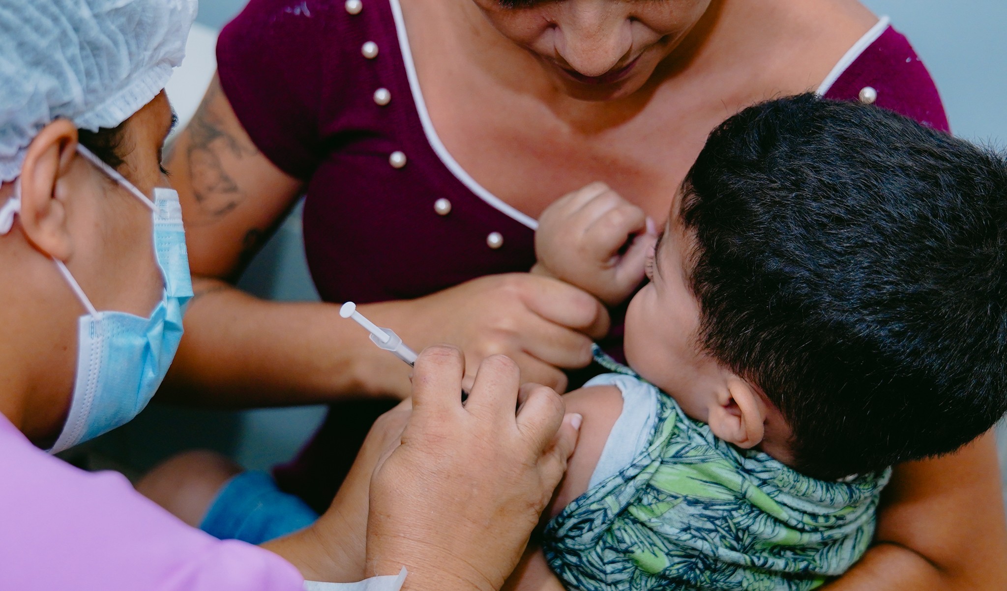 enfermeira vacina uma criança que está no colo da mãe